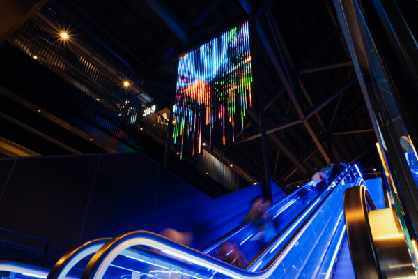 LED light strips forms a large screen installation hanging above a staircase.