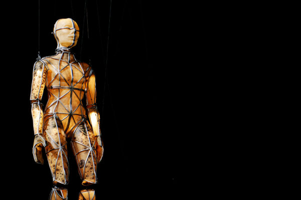 A large puppet made from a metal frame and glowing body.