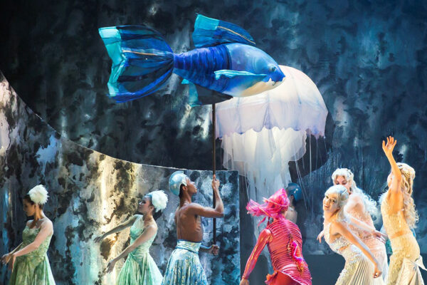 Dancers on stage with a fish puppet prop.