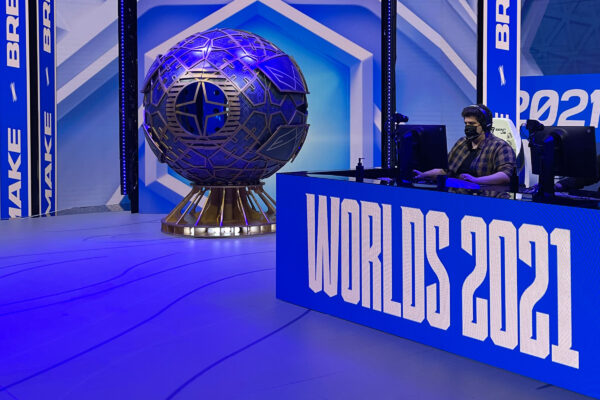 People sat at gaming computers competing in a gaming competition with a large trophy stand in the background.