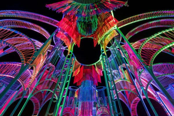 A colourful art installation comprised of woven colourful string around a metal structure.