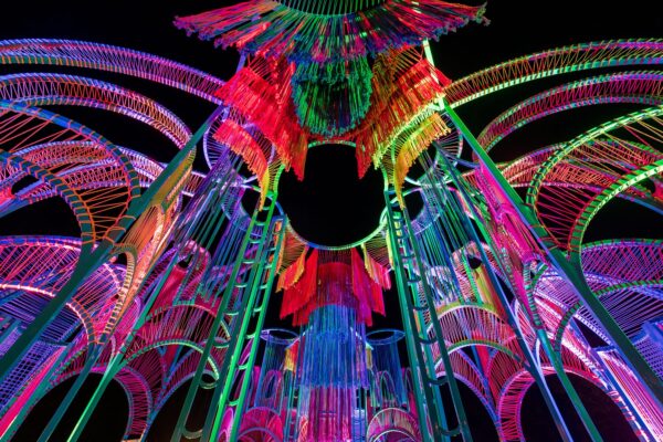 A colourful art installation comprised of woven colourful string around a metal structure.