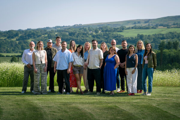 Team photo in front of a countryside landscape.