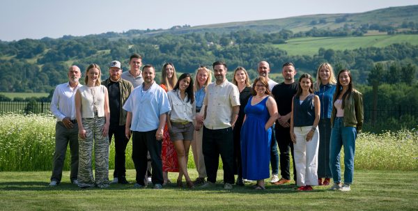 Team photo in front of a countryside landscape.
